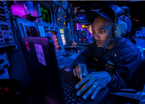 A Navy seaman viewing a computer onboard a ship